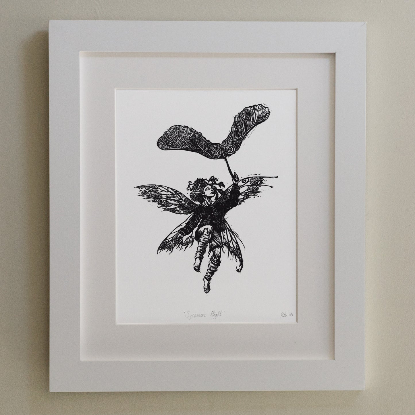 Framed black and white illustration of a fairy on a beige wall