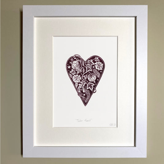 Framed artwork of a heart-shaped design with floral patterns on a beige wall.