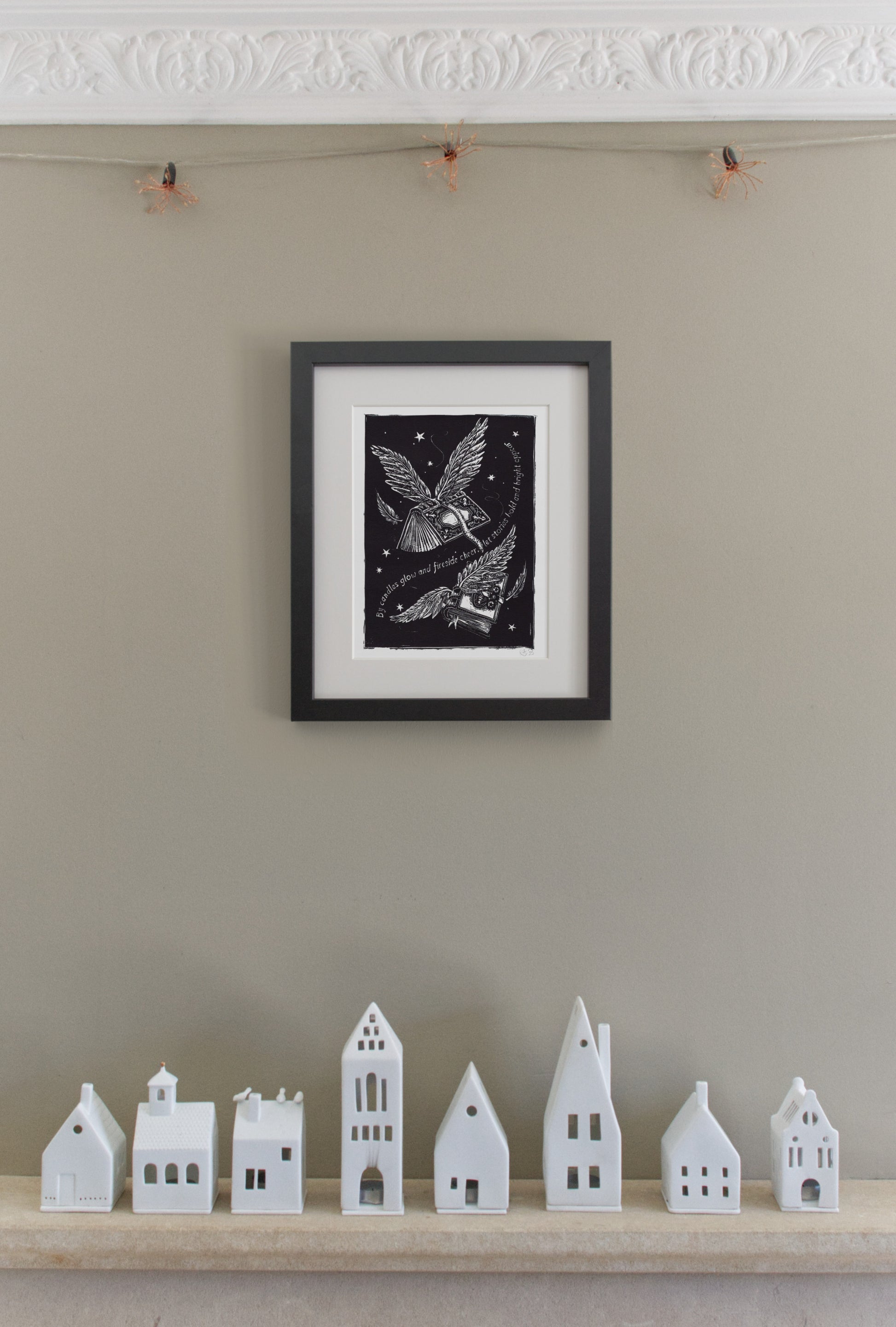 Framed artwork on a wall with small white houses below