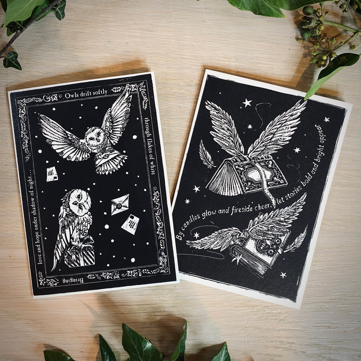 Two black and white cards with owl designs on a wooden surface.
