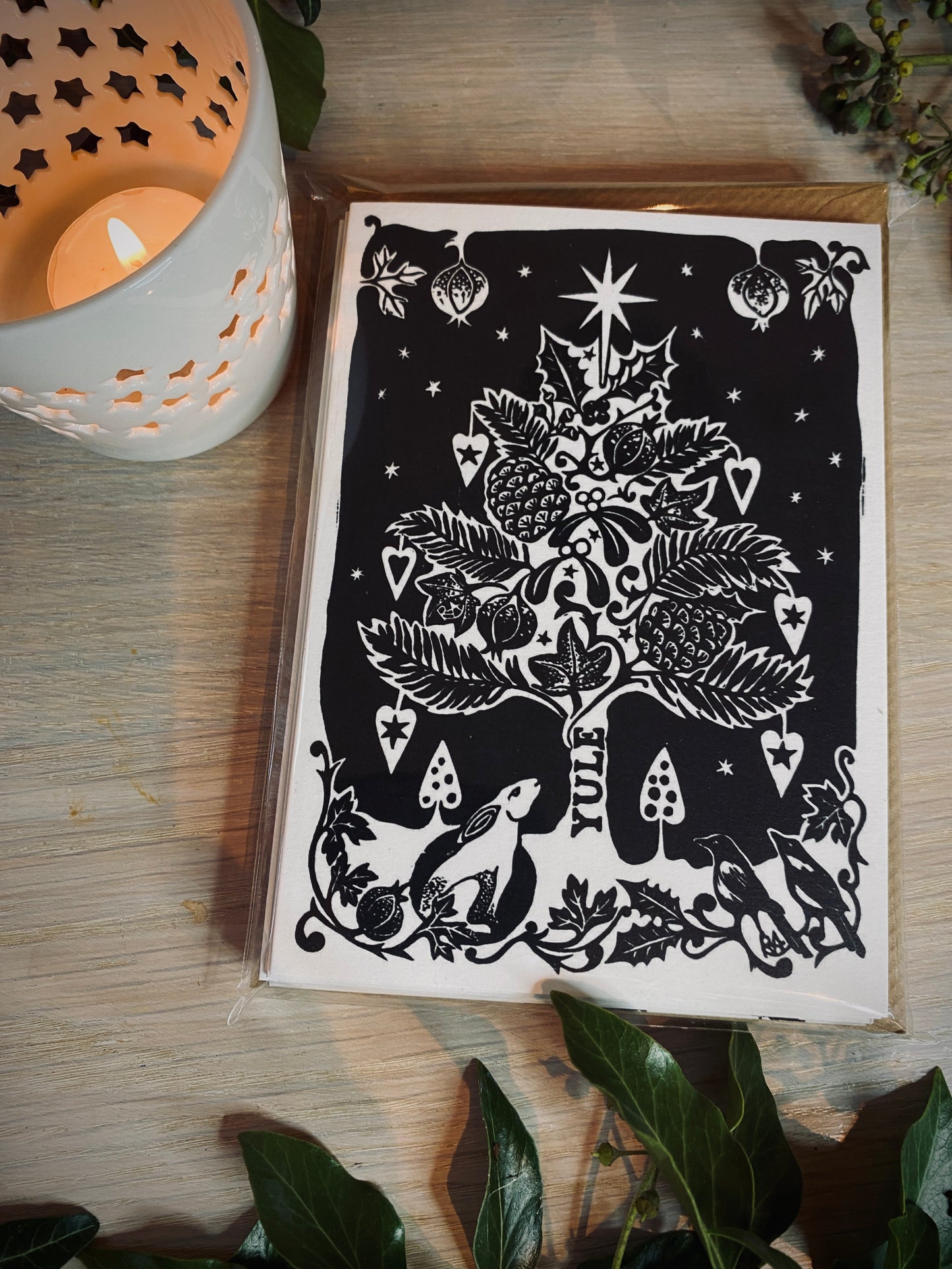 Decorative card with black and white design on a wooden surface with a candle.