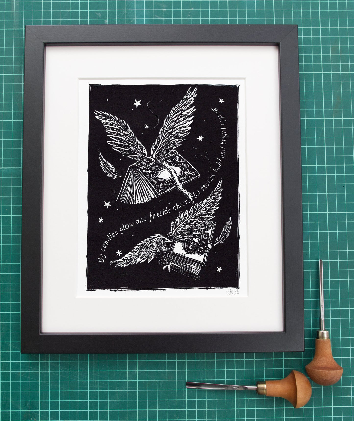 Framed black and white artwork of a winged book on a green grid background with carving tools.