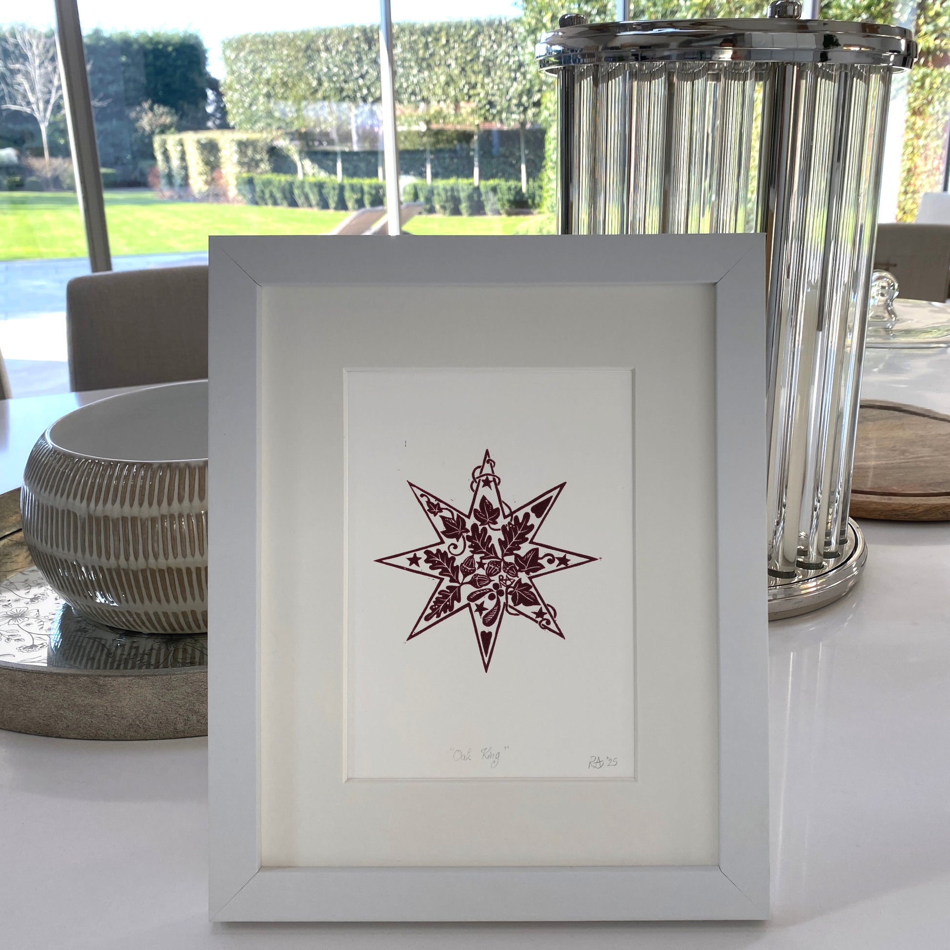Framed artwork of a star design on a table with decorative elements.