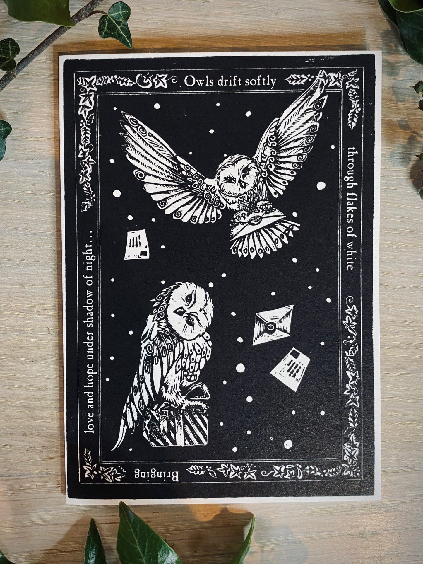 Black and white illustration of owls with decorative text on a wooden surface