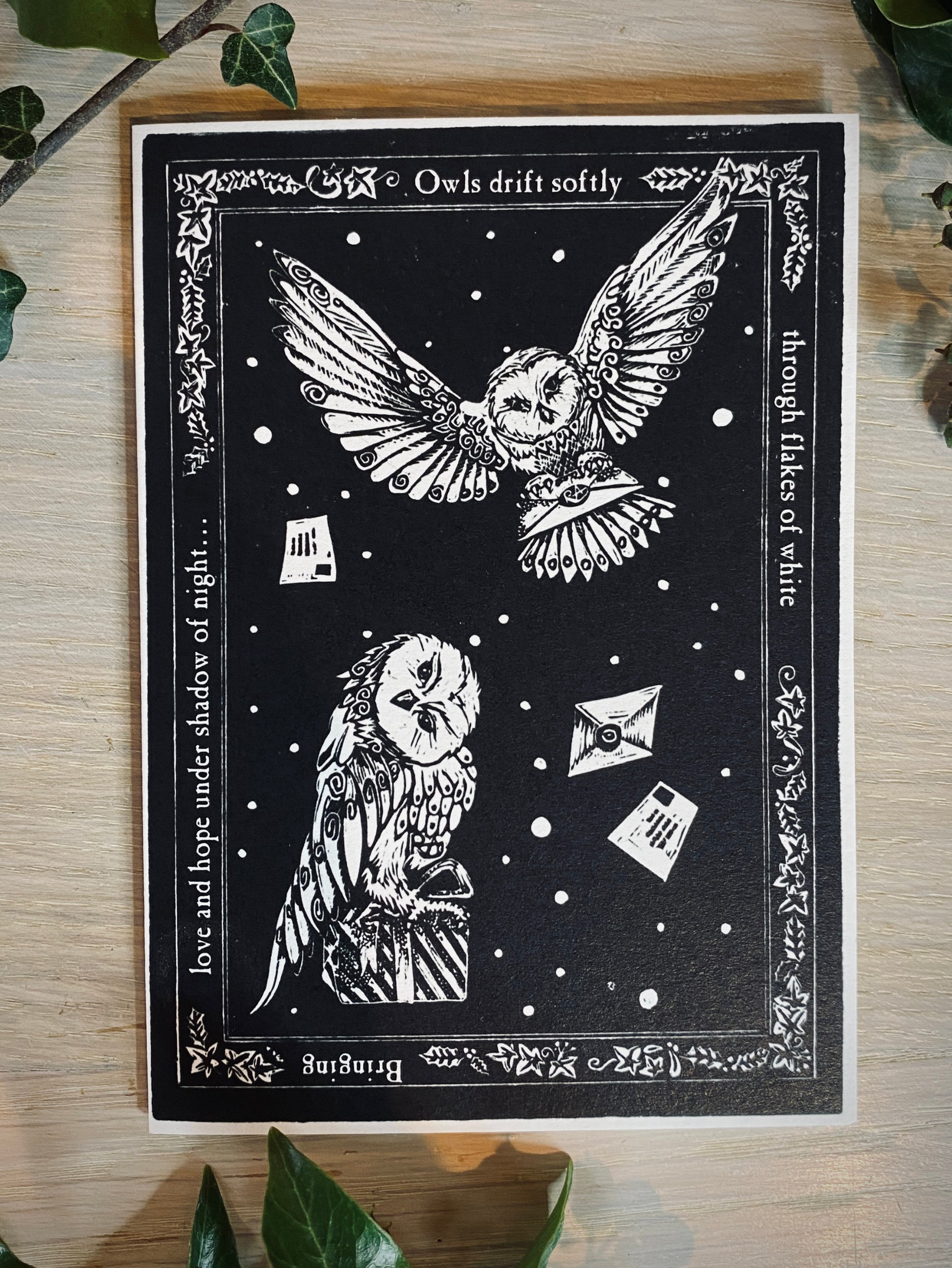 Black and white illustration of owls with decorative text on a wooden surface