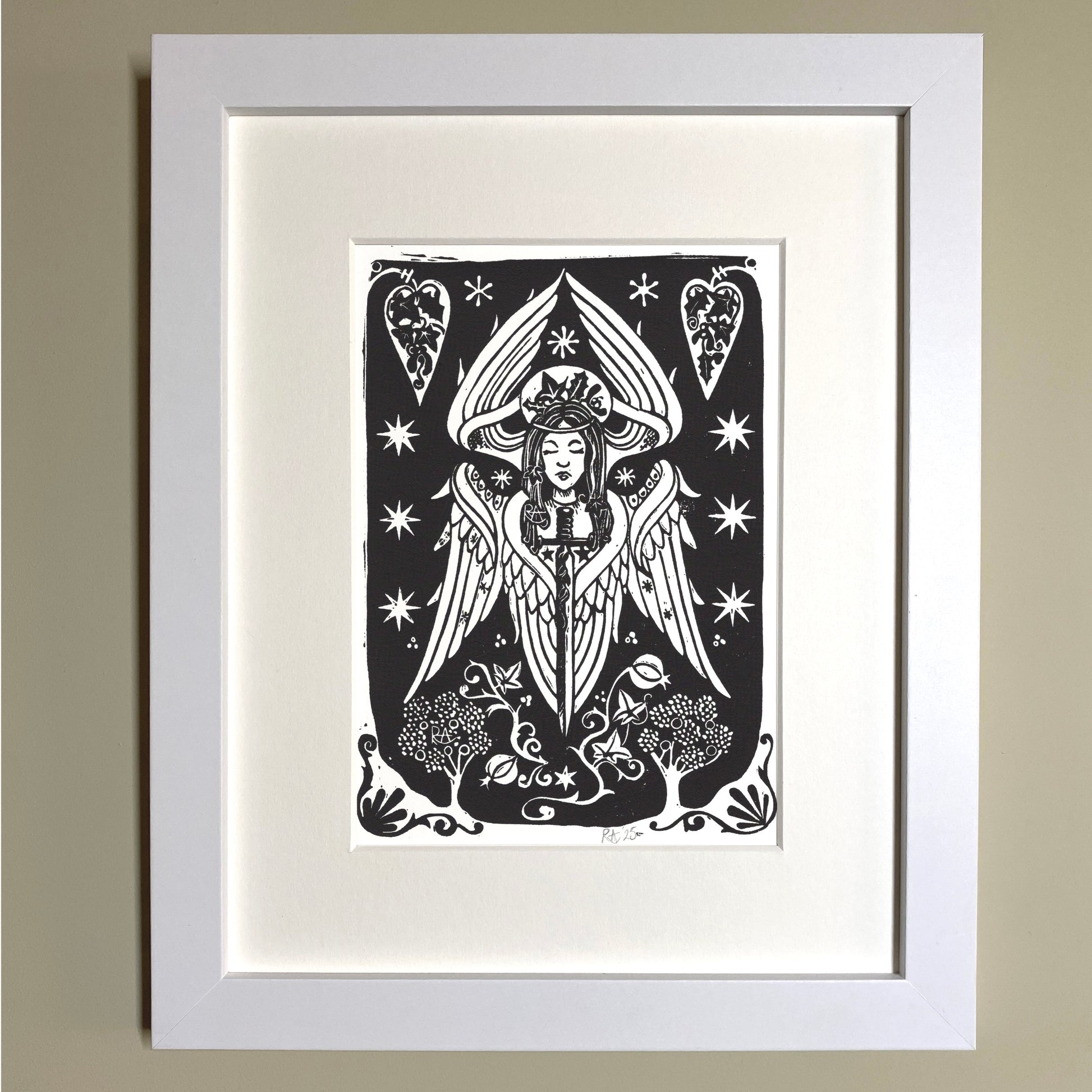 Framed black and white artwork of a stylized angel with stars and hearts on a beige wall.