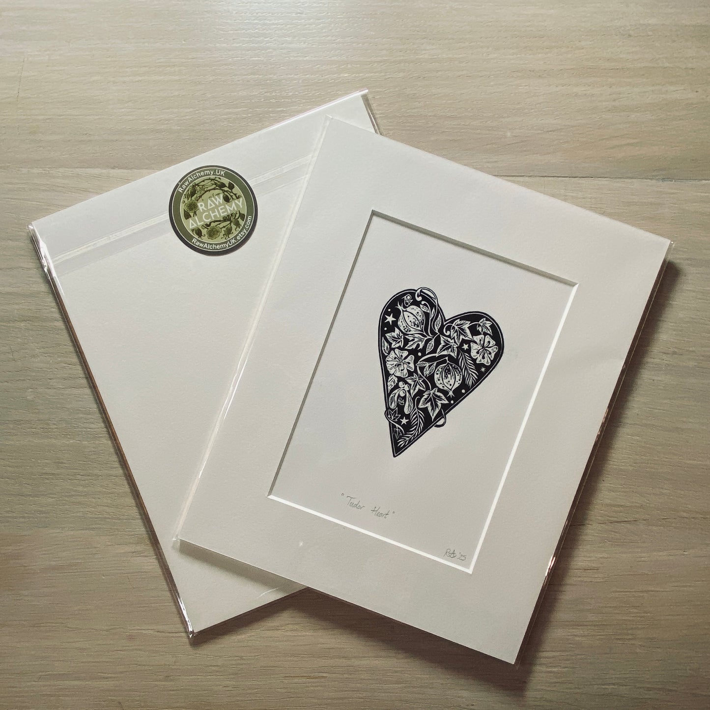 Matted artwork of a heart with floral details on a wooden surface