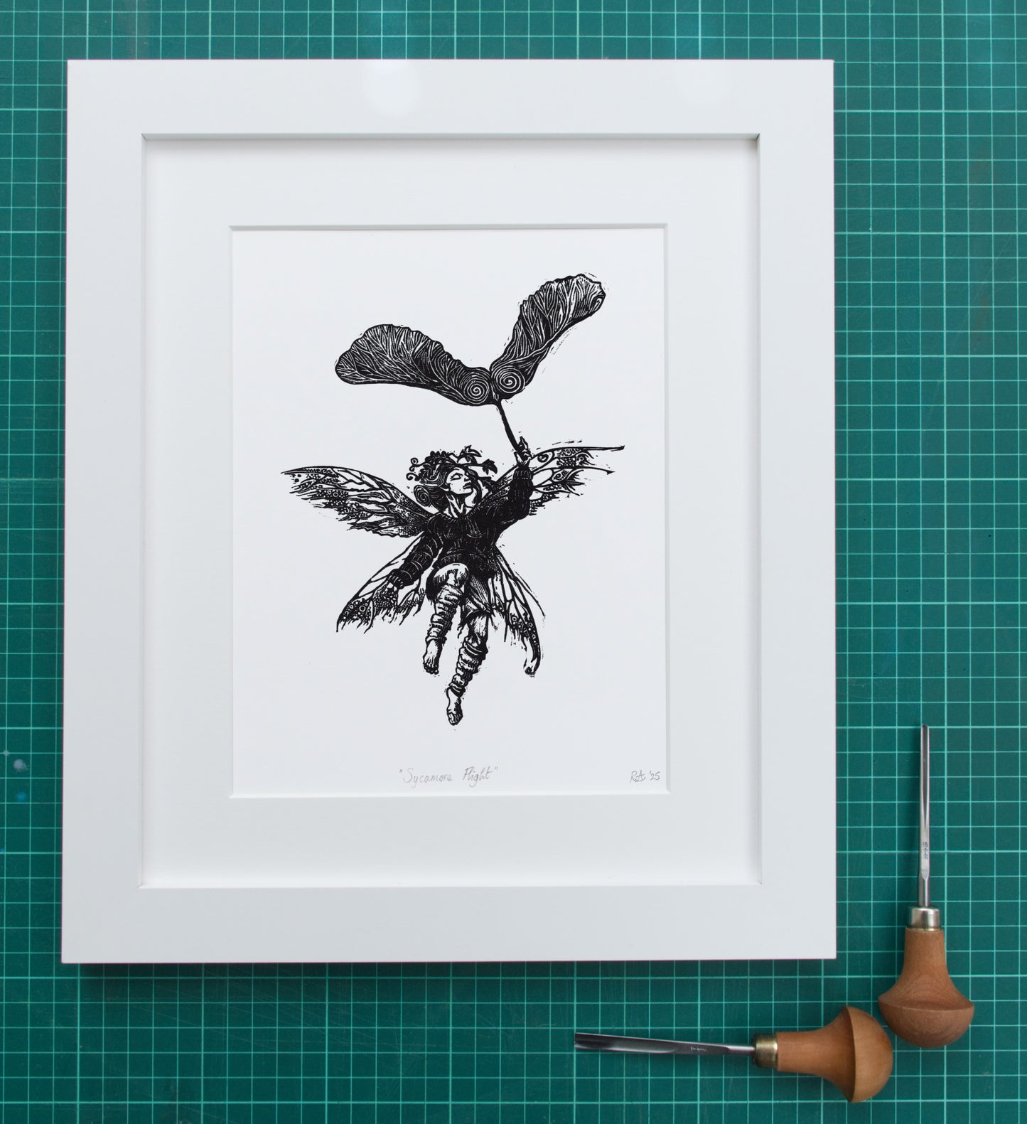 Framed black and white illustration of a fairy on a green grid background