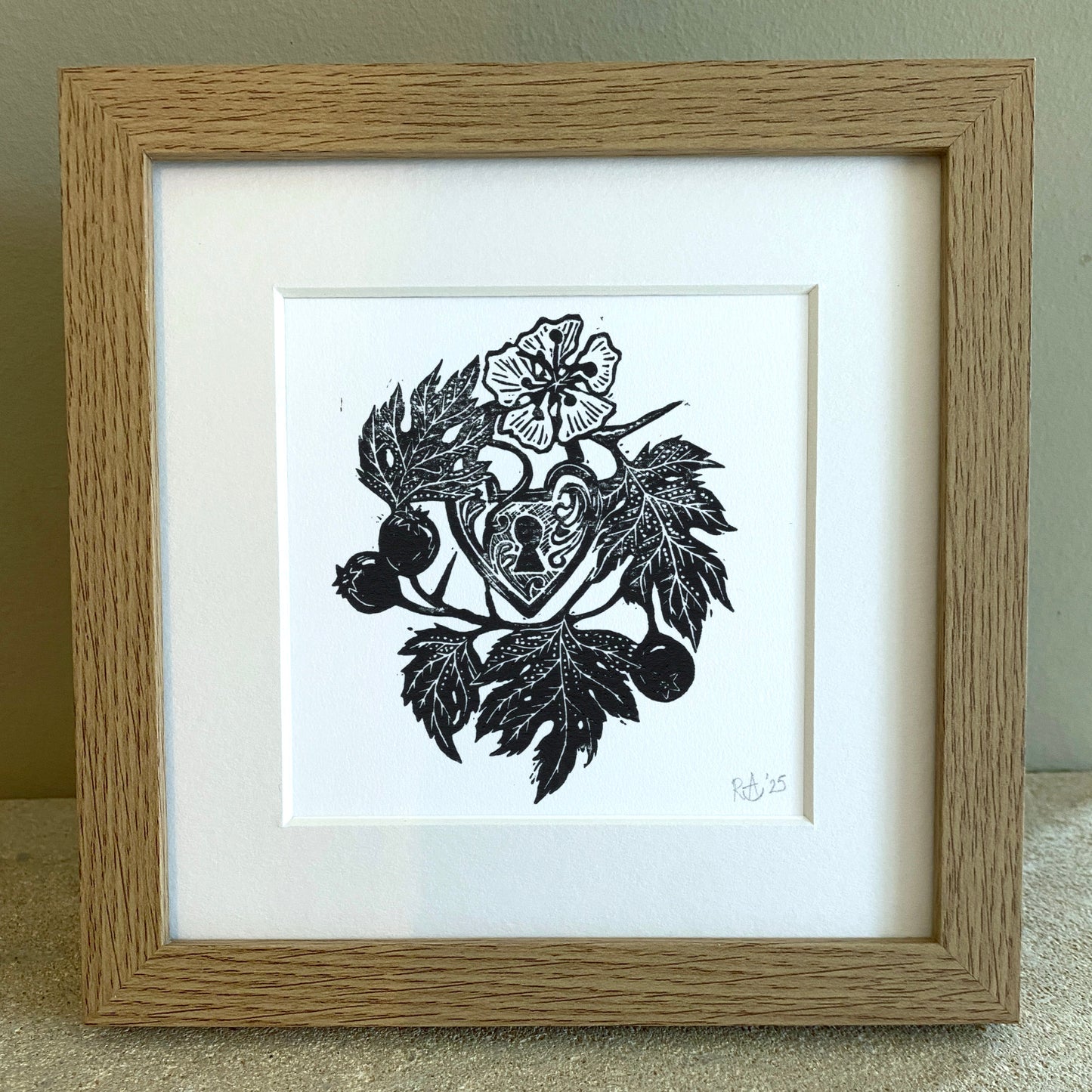 Framed artwork with black leaf and heart design on a white background