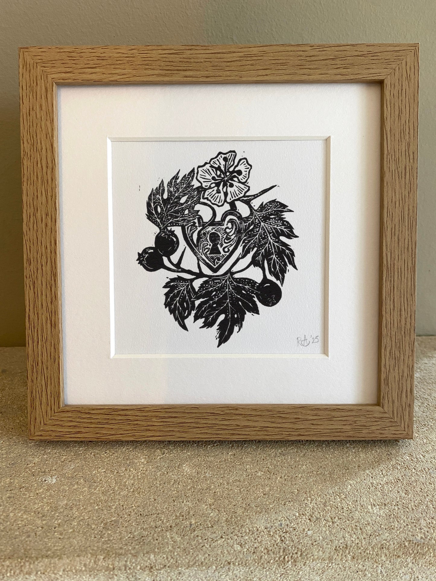 Framed black and white artwork with a heart design on a textured surface.