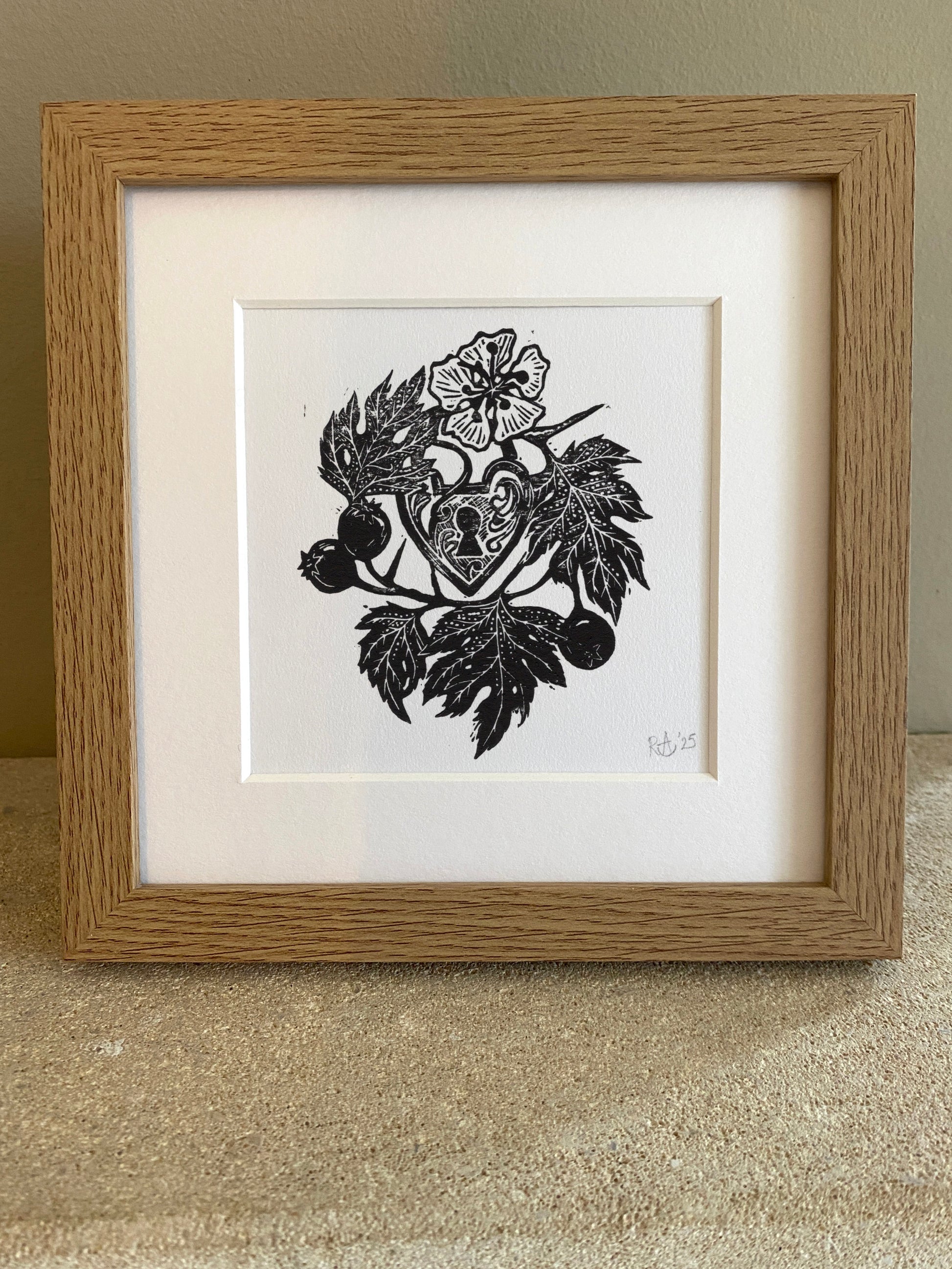 Framed black and white artwork with a heart design on a textured surface.