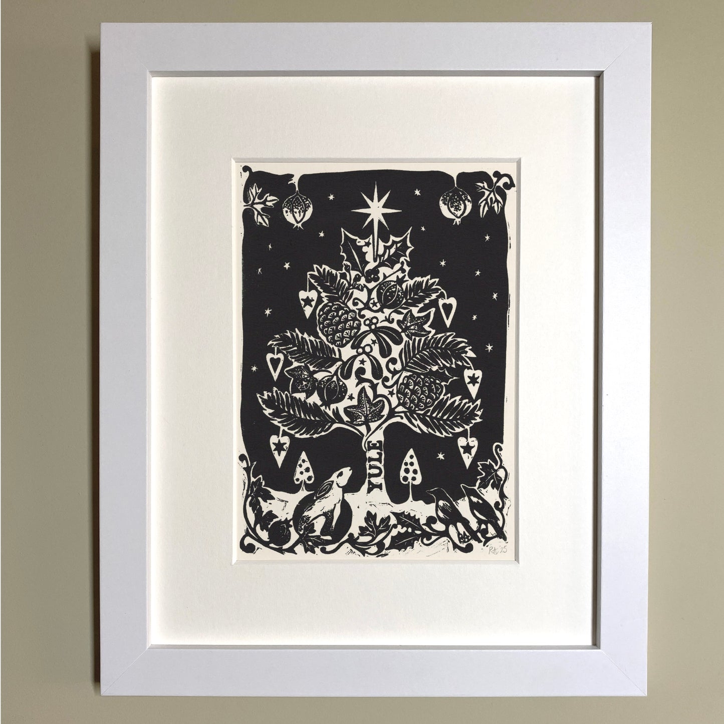 Framed black and white illustration of a Christmas tree on a beige wall