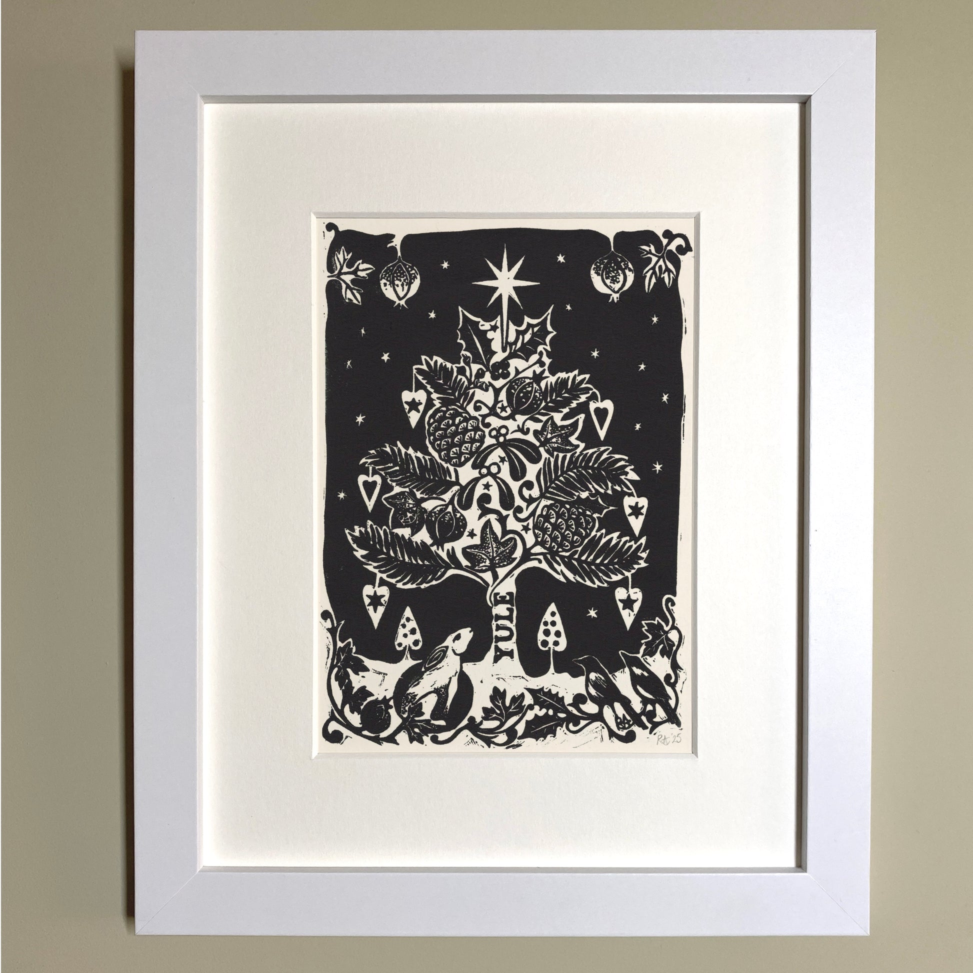 Framed black and white illustration of a Christmas tree on a beige wall