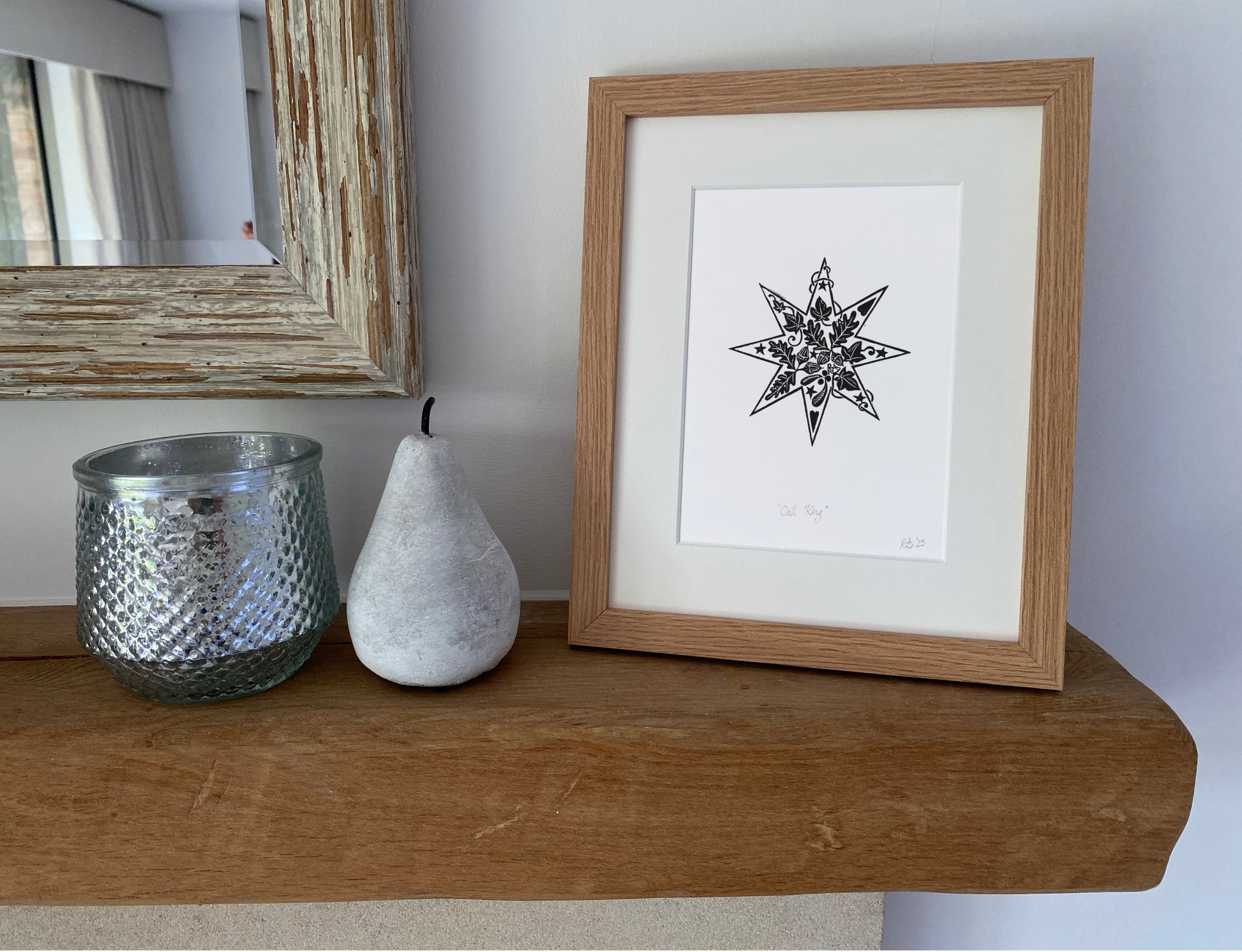 Framed black and white star artwork on a wooden shelf with decorative items.