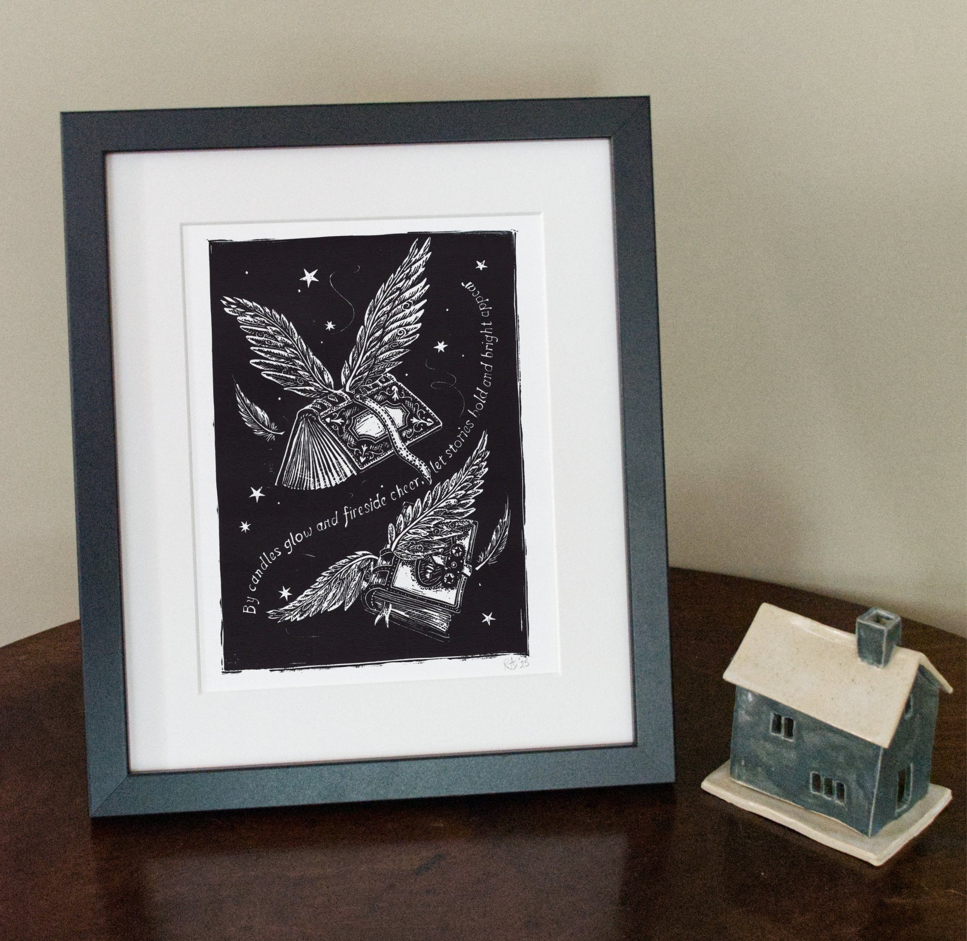 Framed artwork with a black and white illustration of birds and text on a wooden surface.