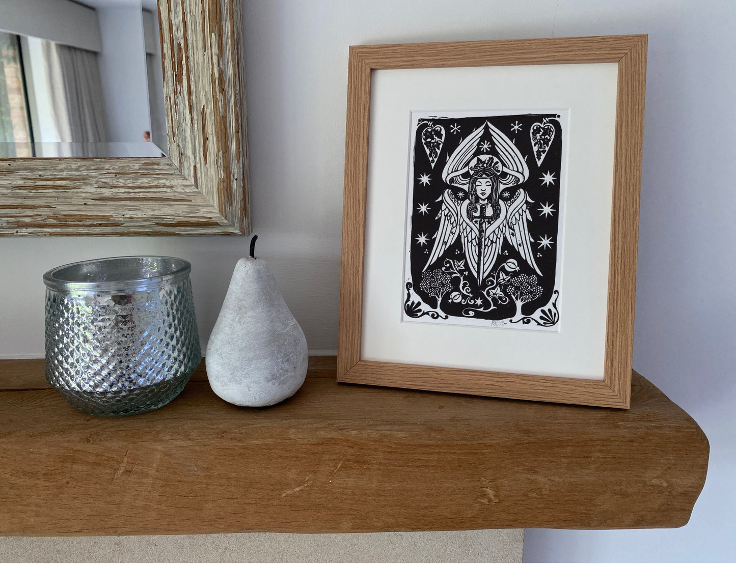 Framed artwork on a wooden shelf with decorative items