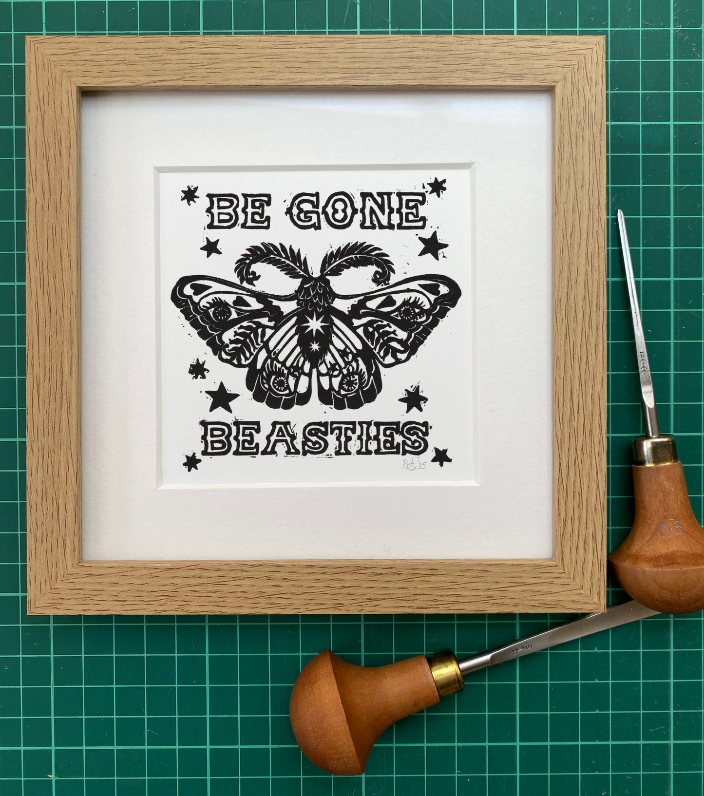 Framed black and white print with butterfly design and text on a green grid background