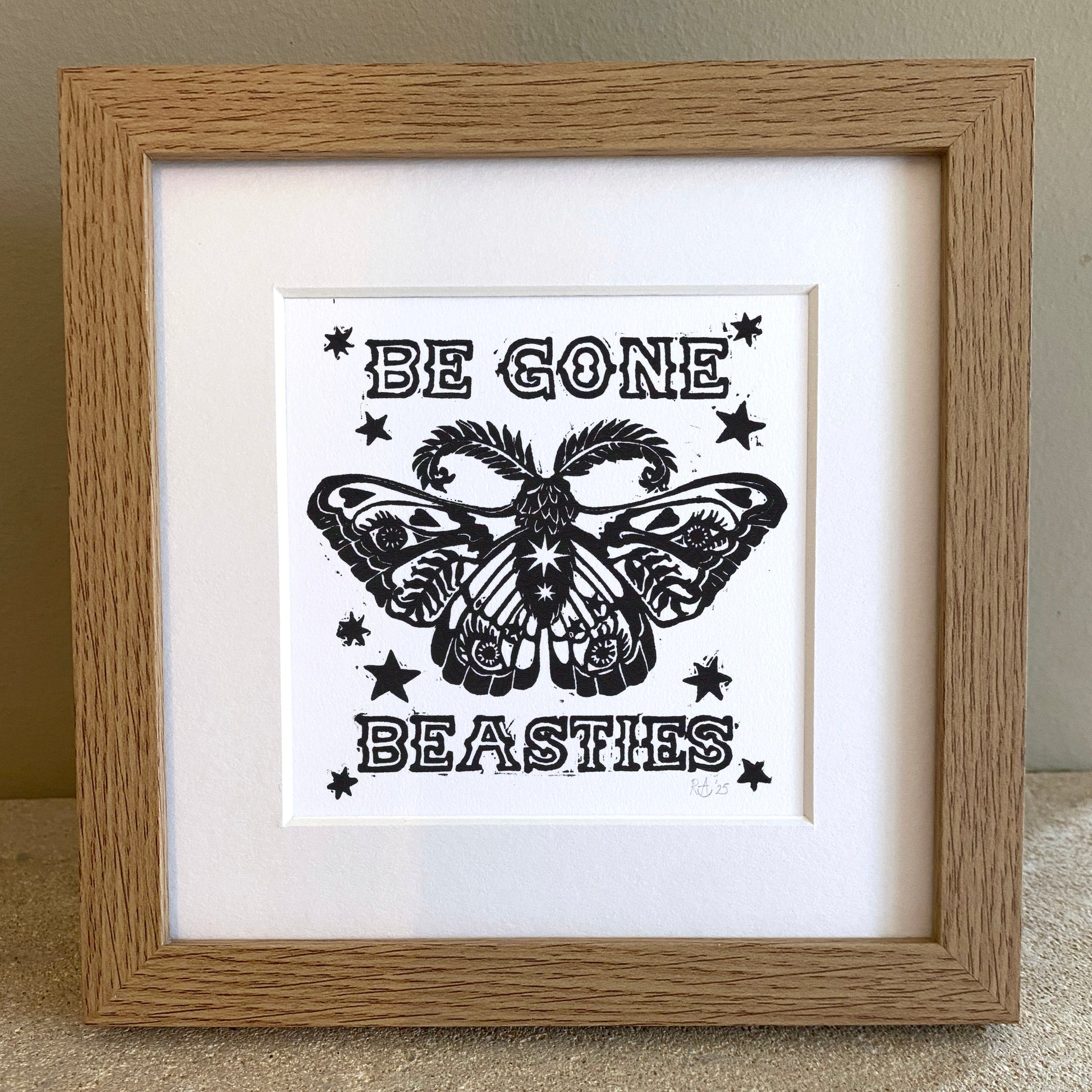 Framed artwork with butterfly design and text 'Be Gone Beasties' on a white background.