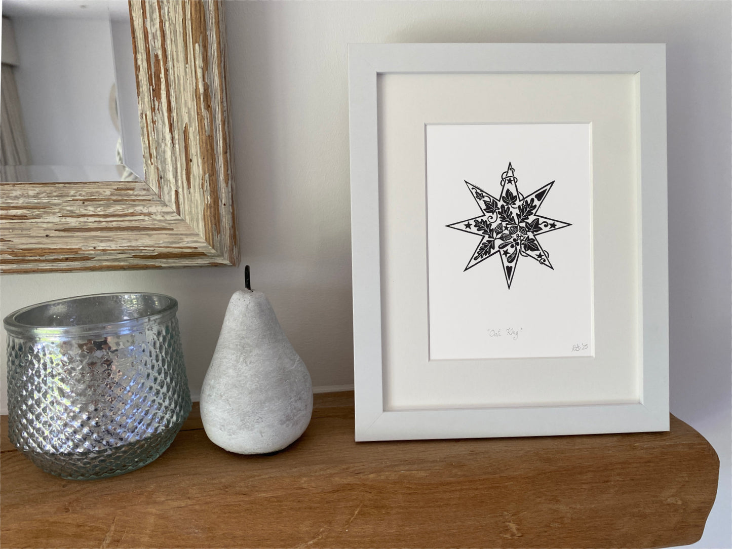 Framed black and white star art print on a wooden surface with decorative items.