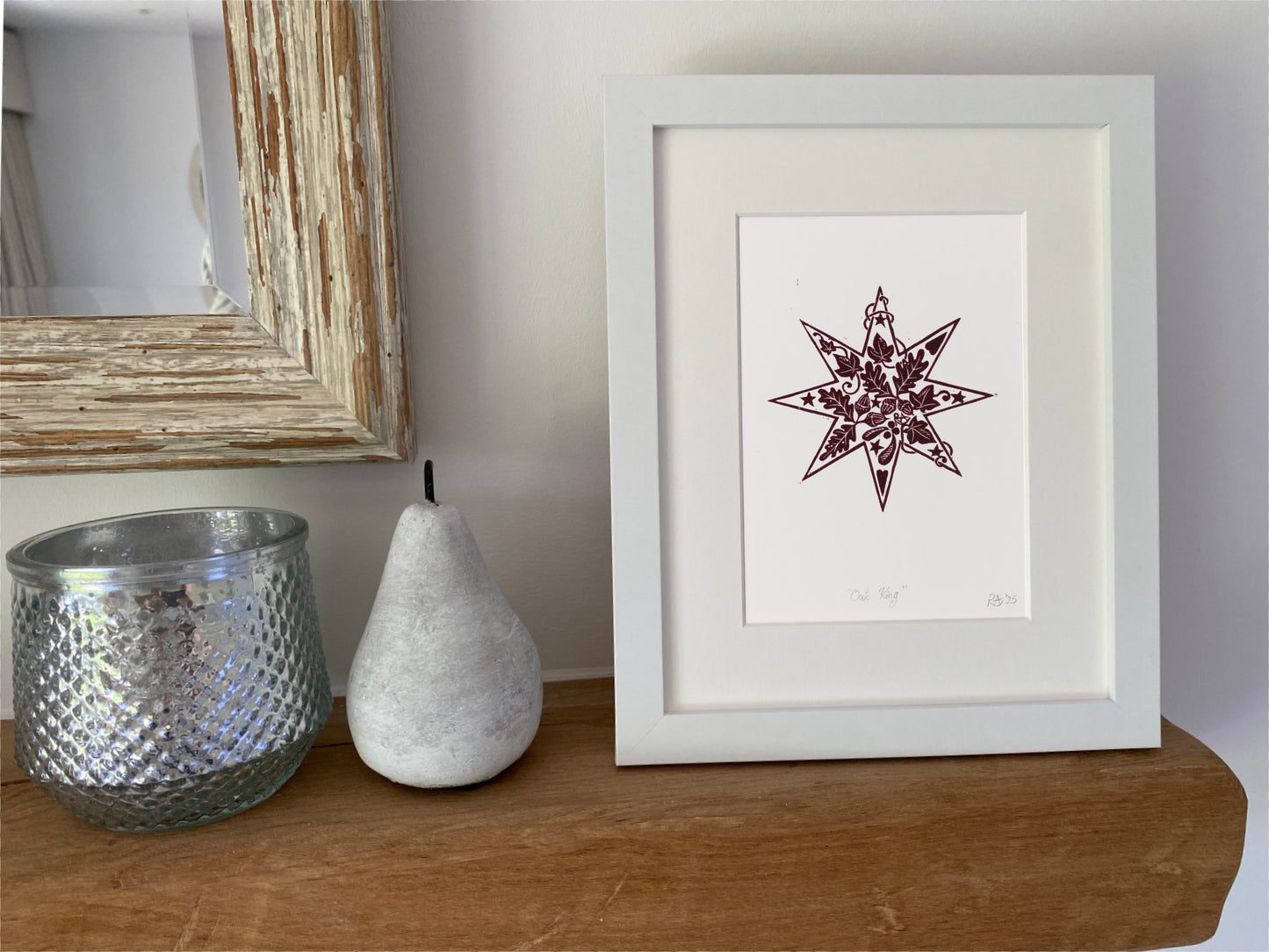 Framed artwork with a star design on a wooden surface next to decorative items.