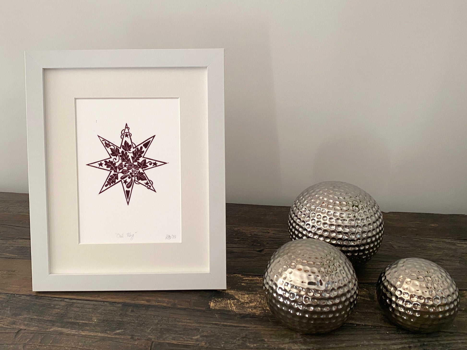 Framed artwork with decorative metallic spheres on a wooden surface