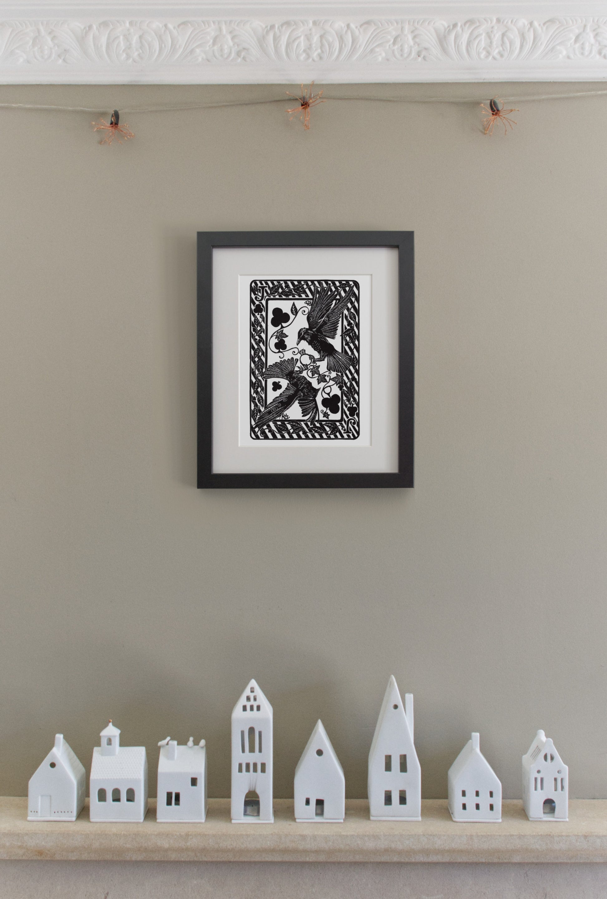 Framed black and white artwork on a wall with small white model houses below.