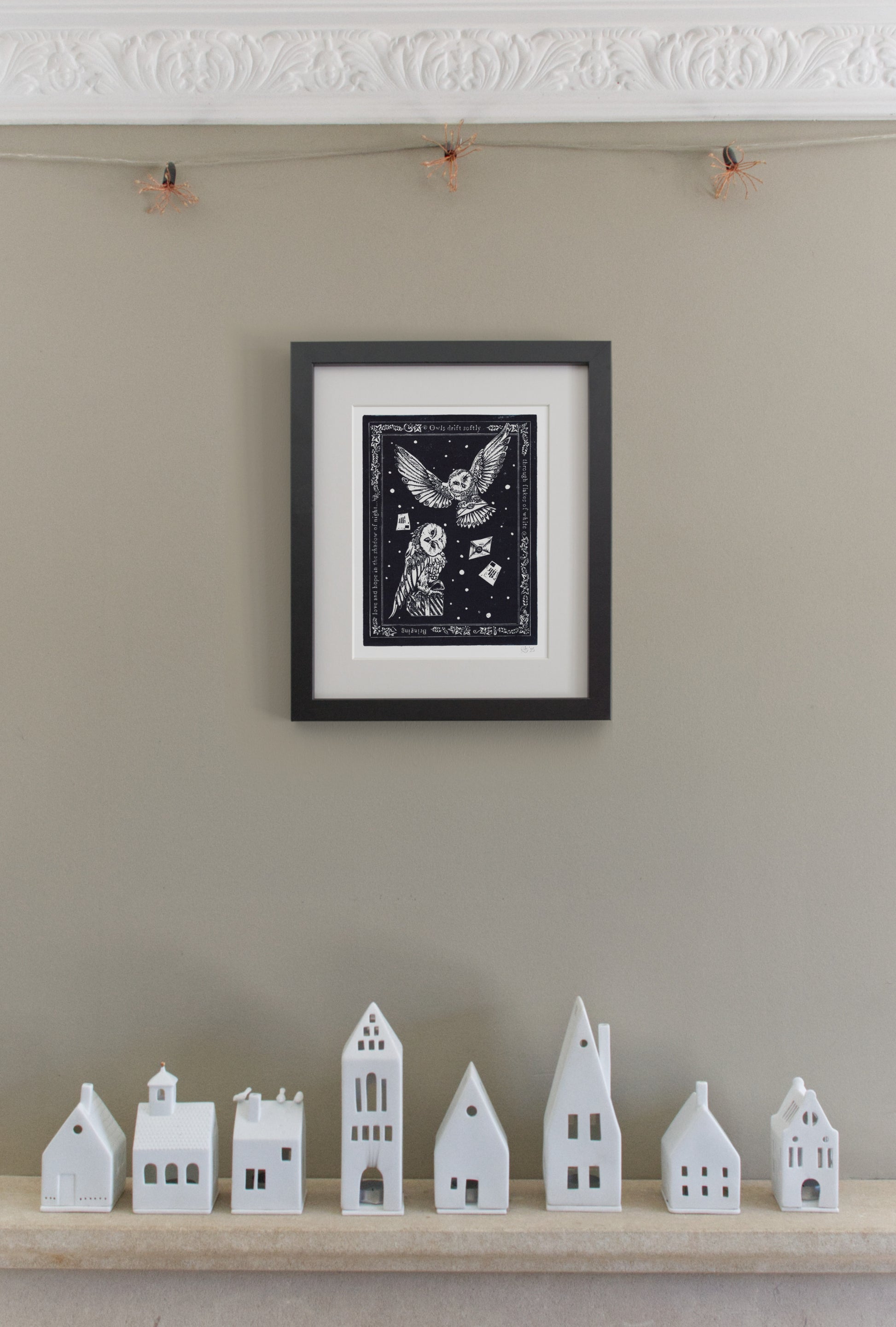 Framed artwork on a wall with small white houses below