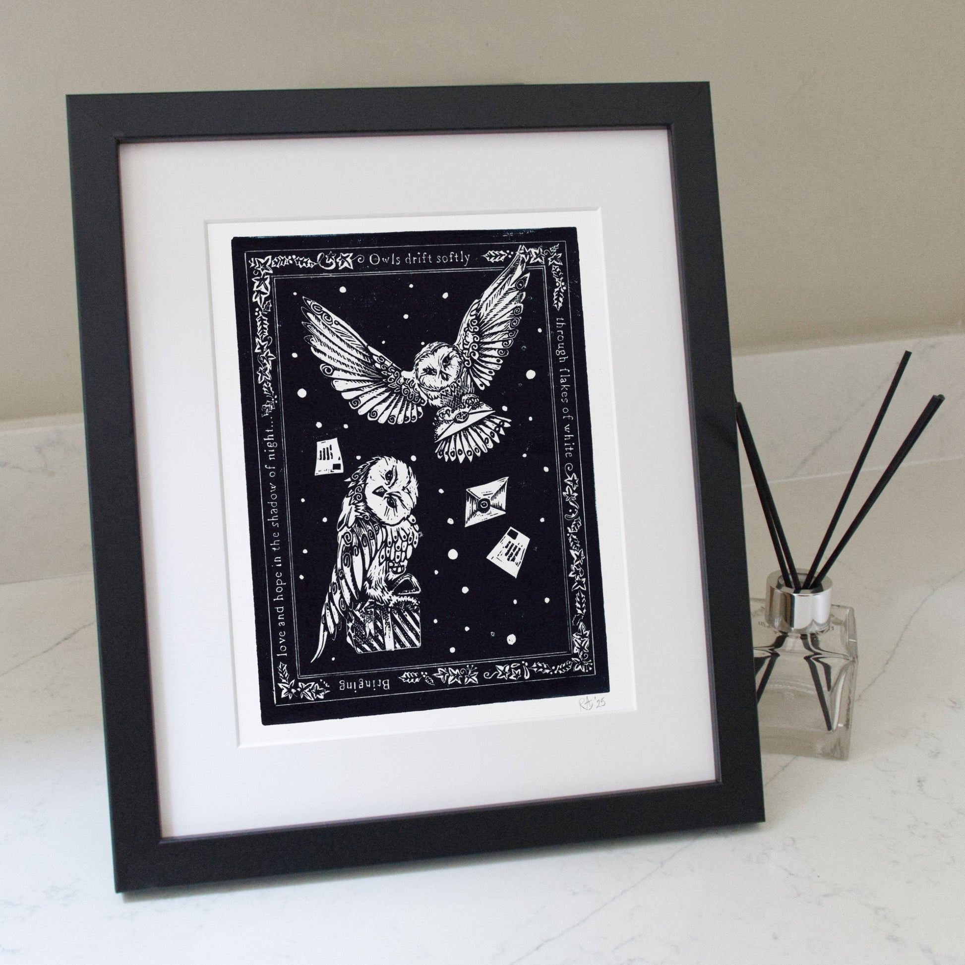 Framed black and white artwork of owls on a white surface with a diffuser in the background.