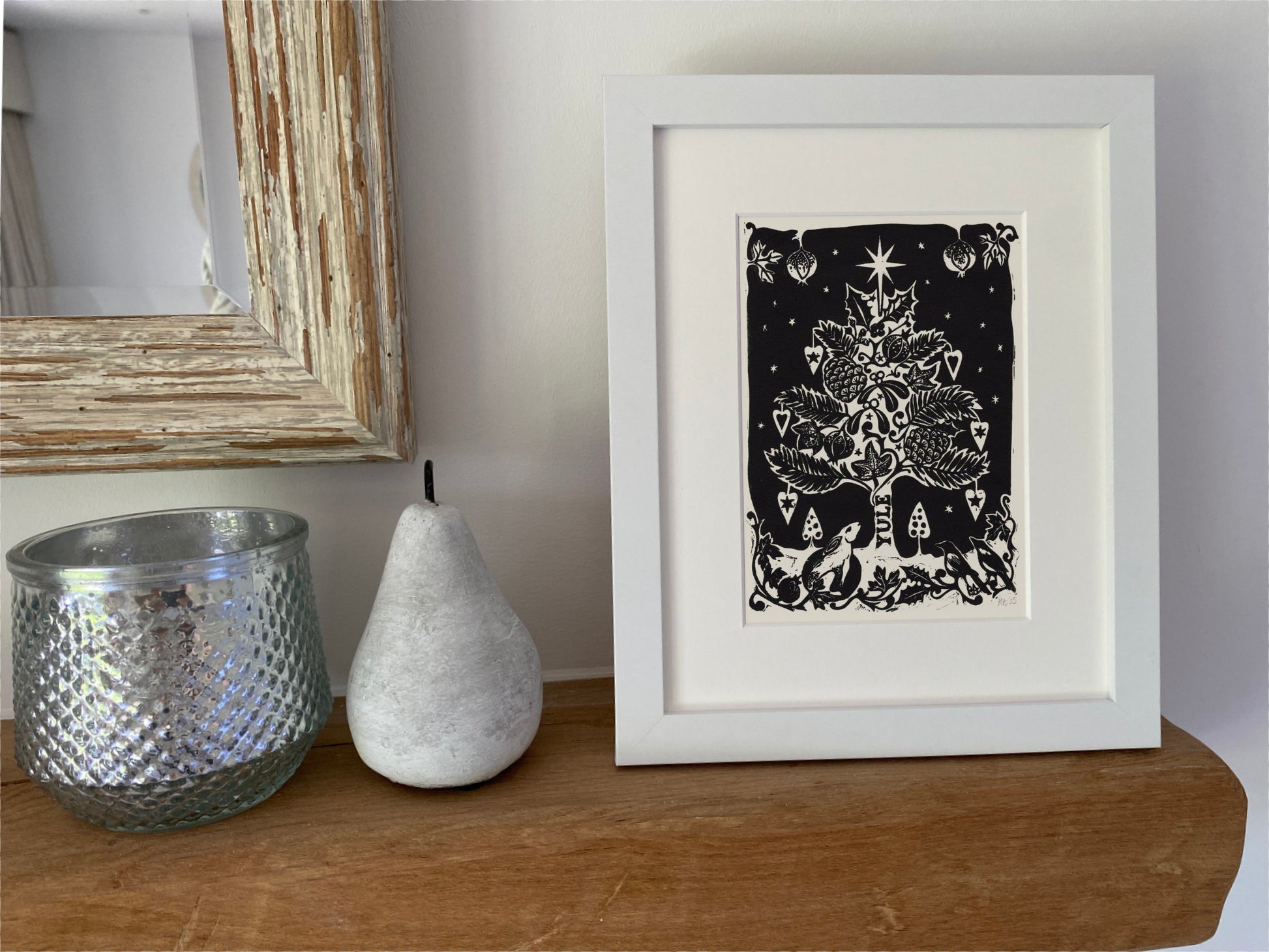Framed artwork of a hare and tree on a wooden surface with decorative items.