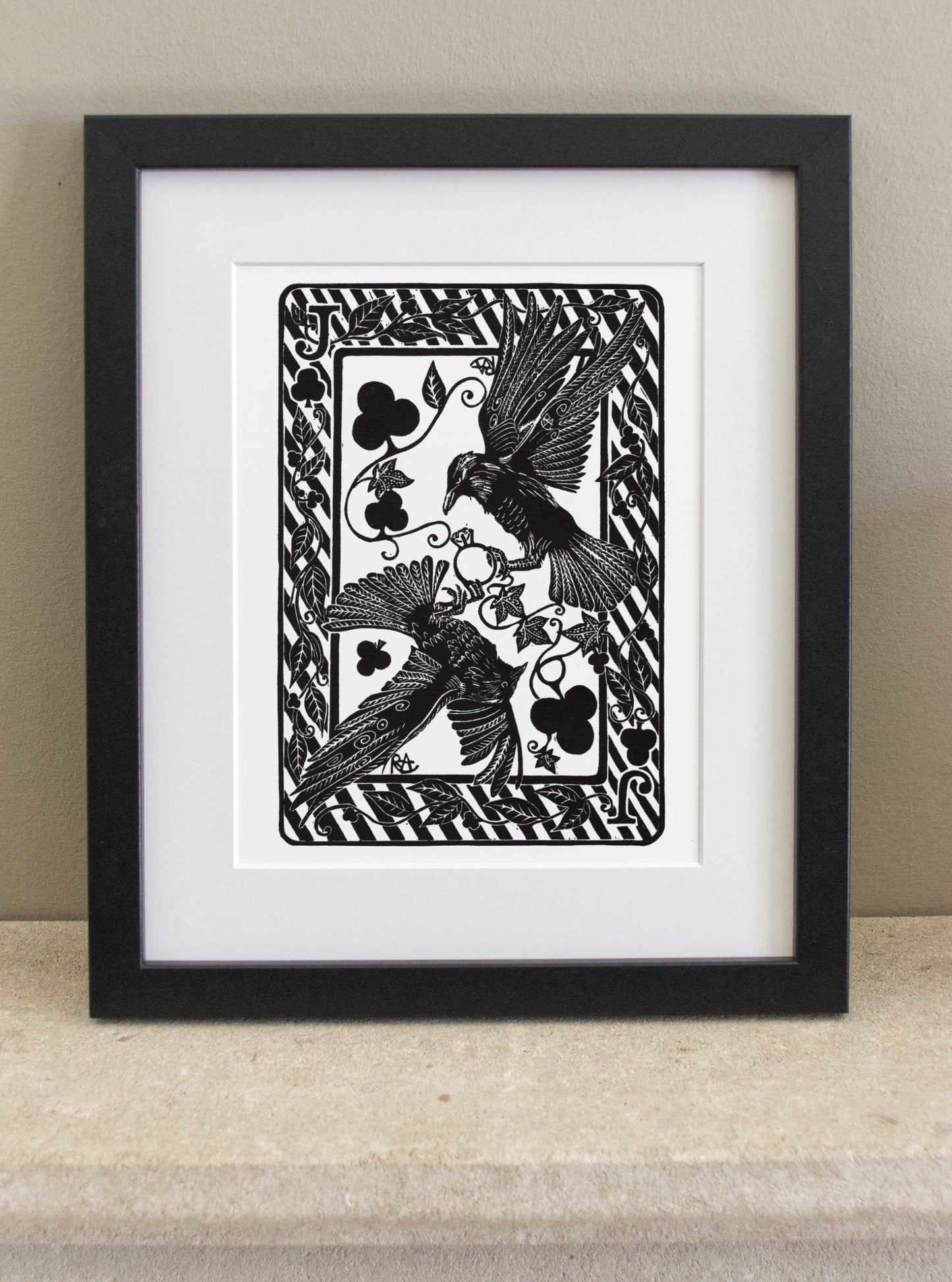 Framed black and white artwork of a bird with floral elements on a beige surface.