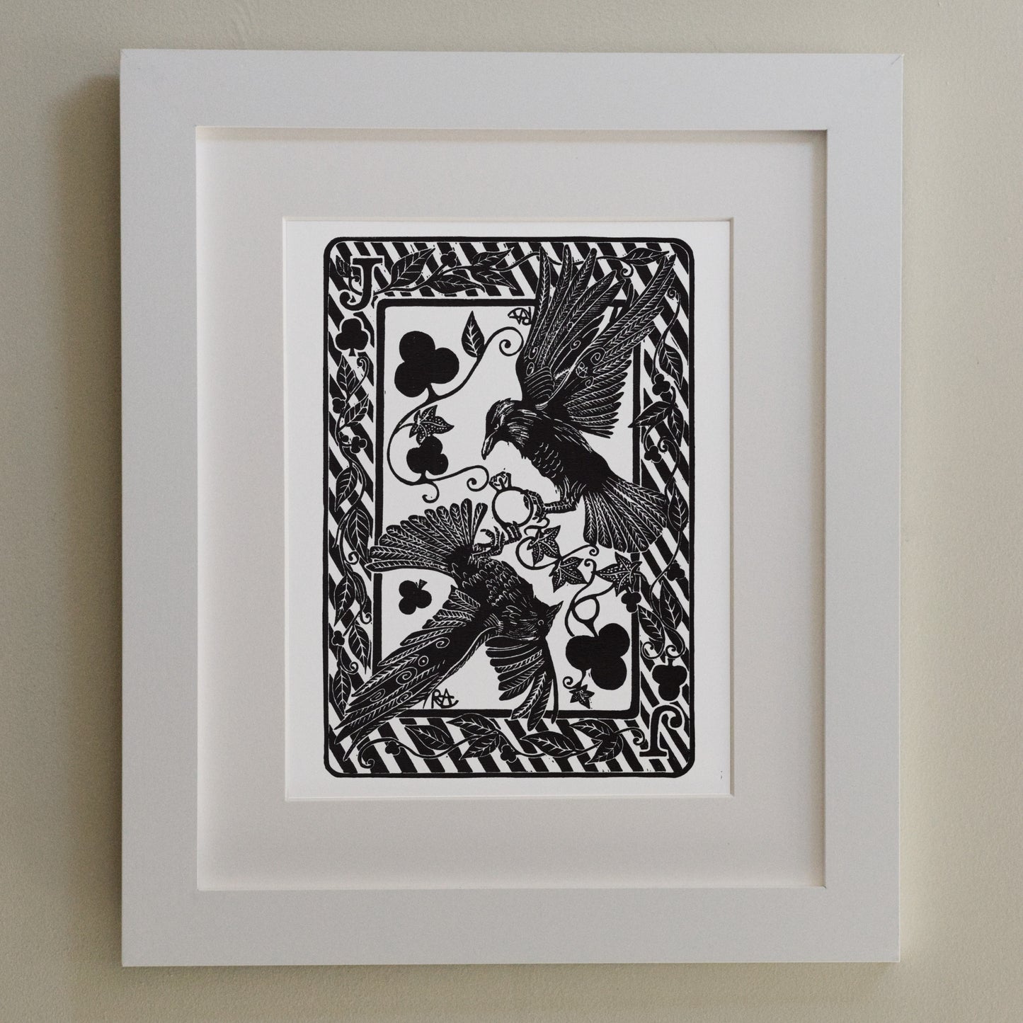 Framed black and white artwork of birds and floral patterns on a beige wall
