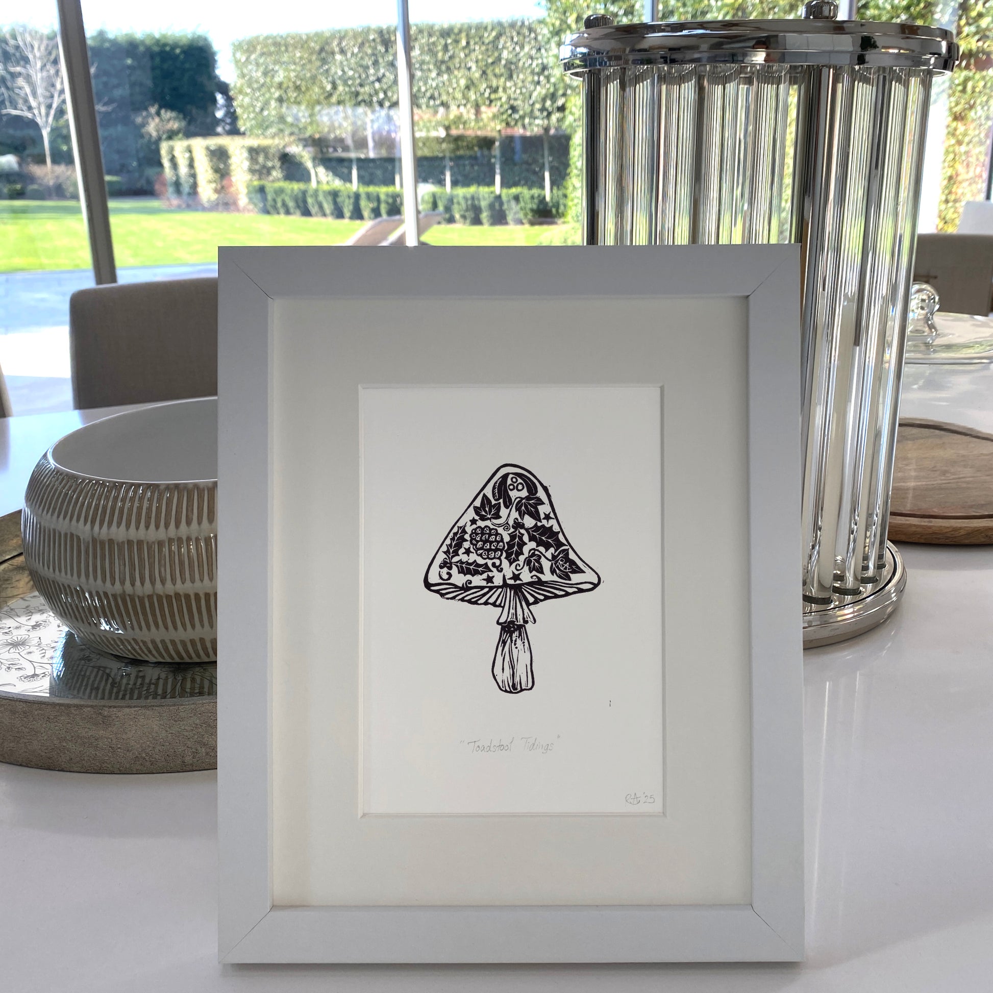 Framed black and white illustration of a mushroom on a table with decorative elements.