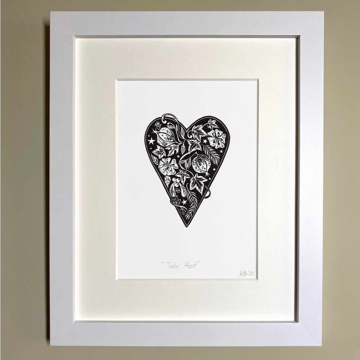 Framed artwork of a black heart-shaped design on a white background