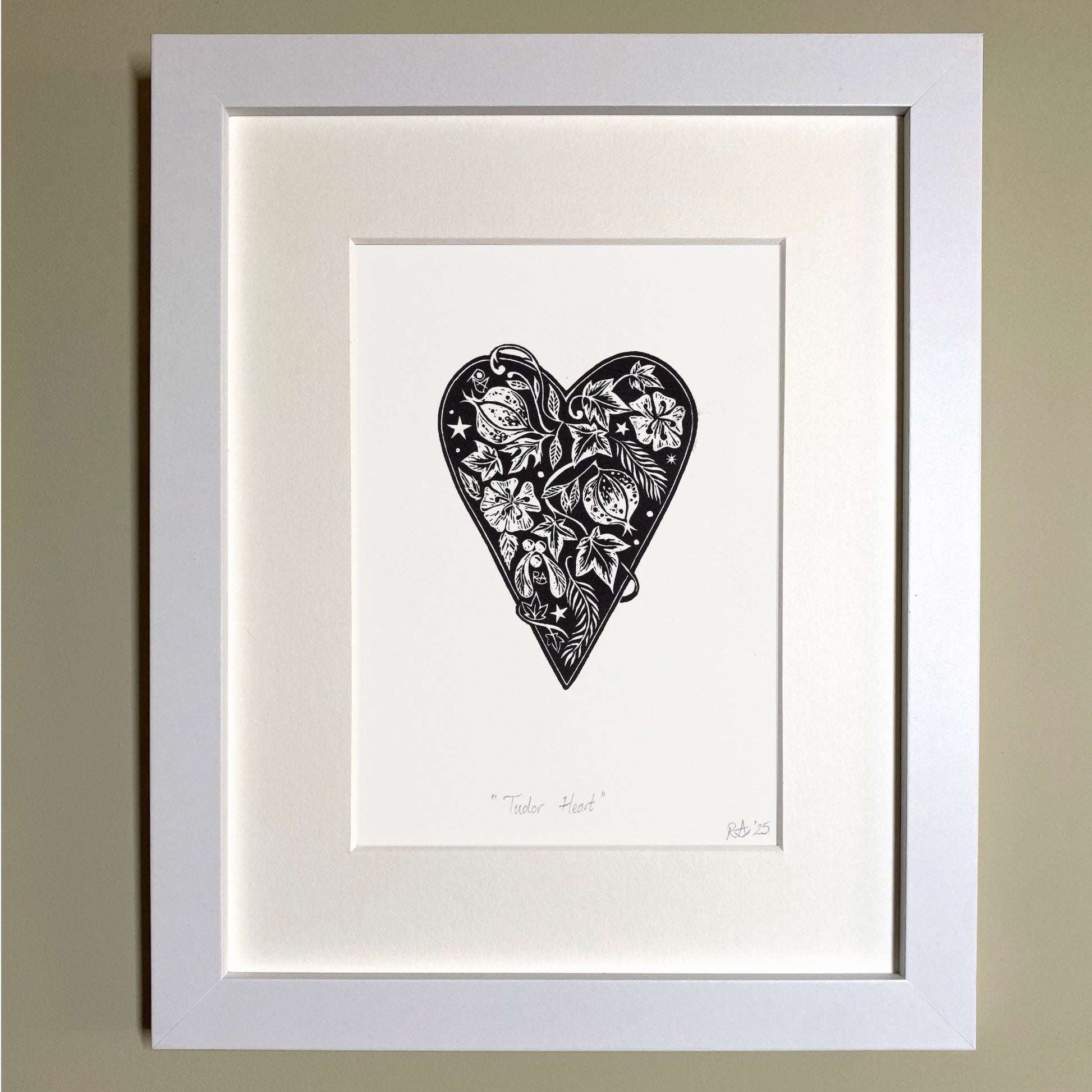 Framed artwork of a black heart-shaped design on a white background